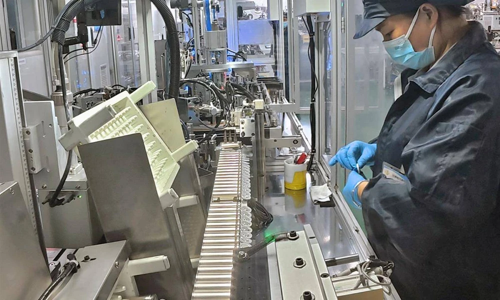 Worker welding a battery cap on a manual cylindrical cell assembly line